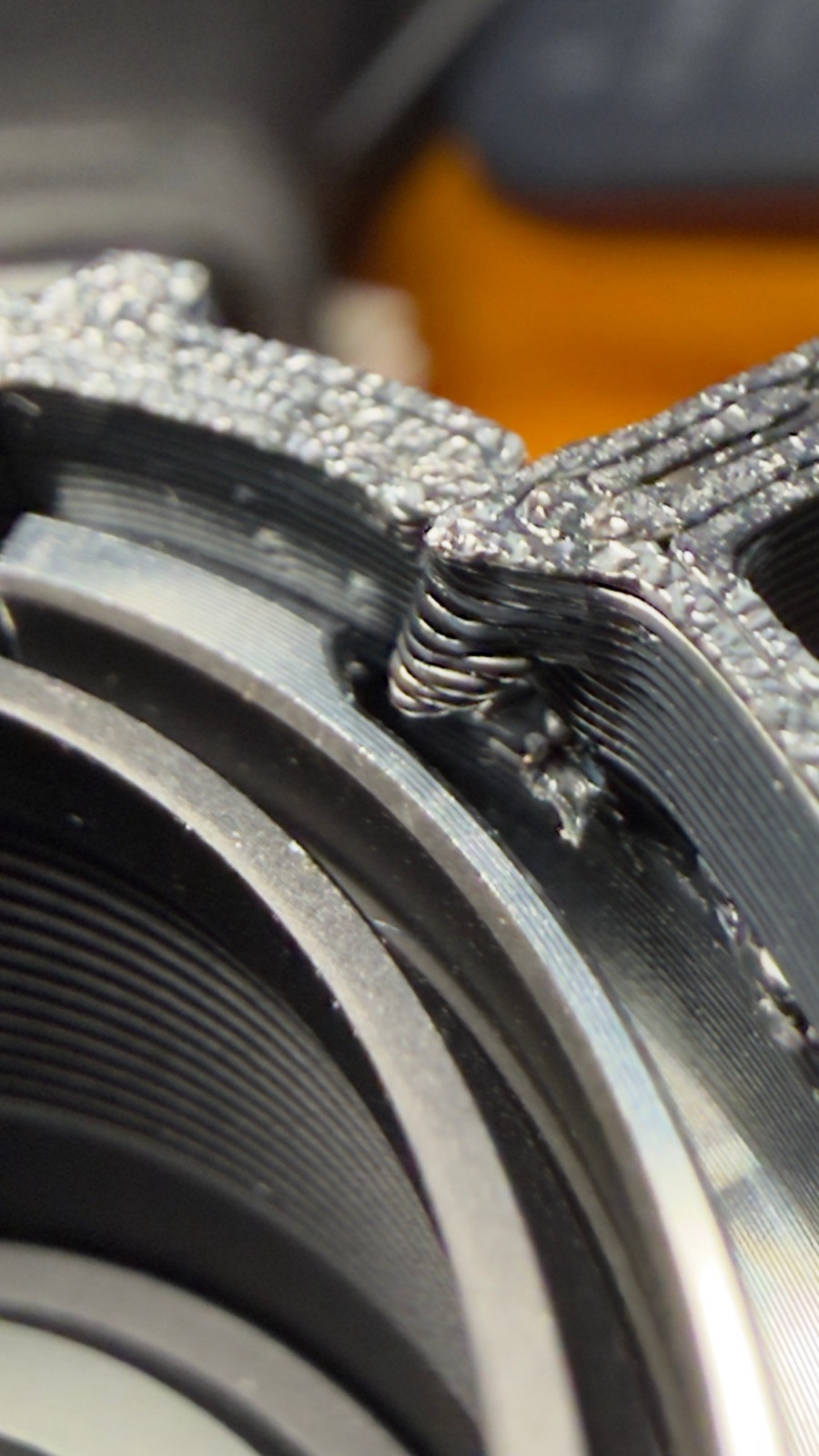Close-up of a black 3D-printed lens-case part against a lens mount